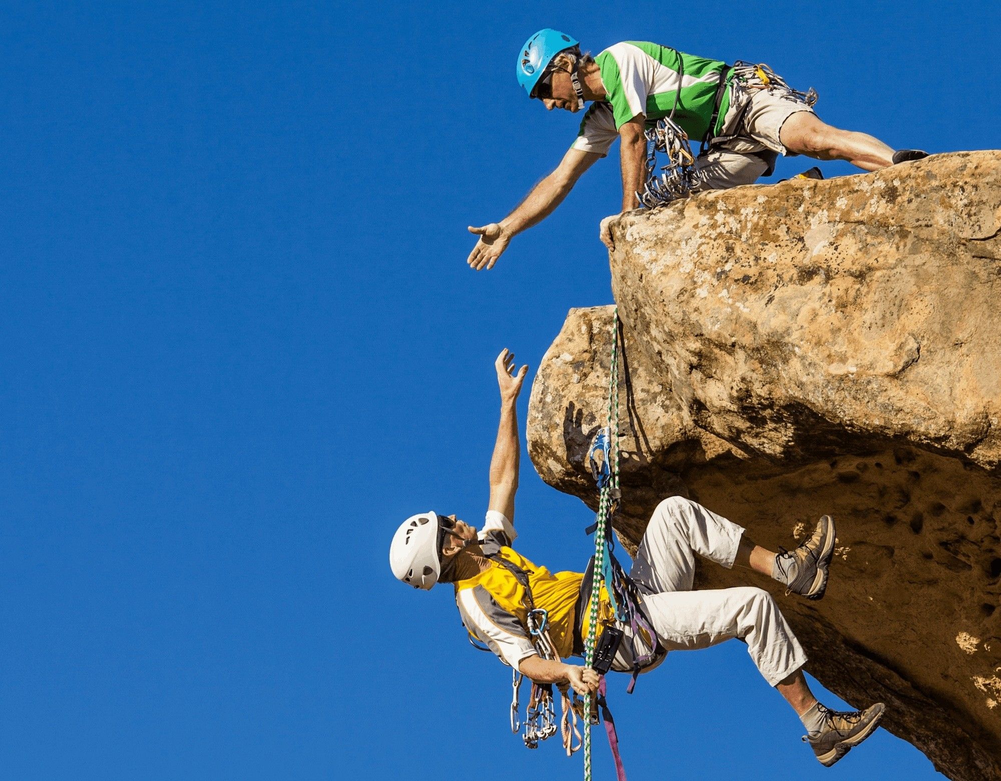 Two climbers on a steep cliff, one helping the other up, symbolizing how addressing readers’ needs lifts your newsletter.