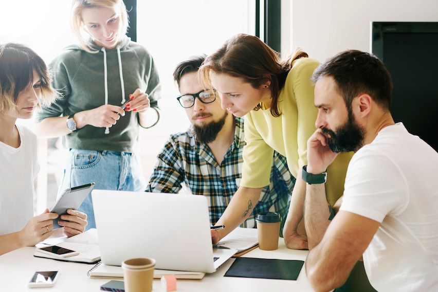 Team collaboratively adjusting targeted mail marketing strategy in front of a notebook during a workshop.