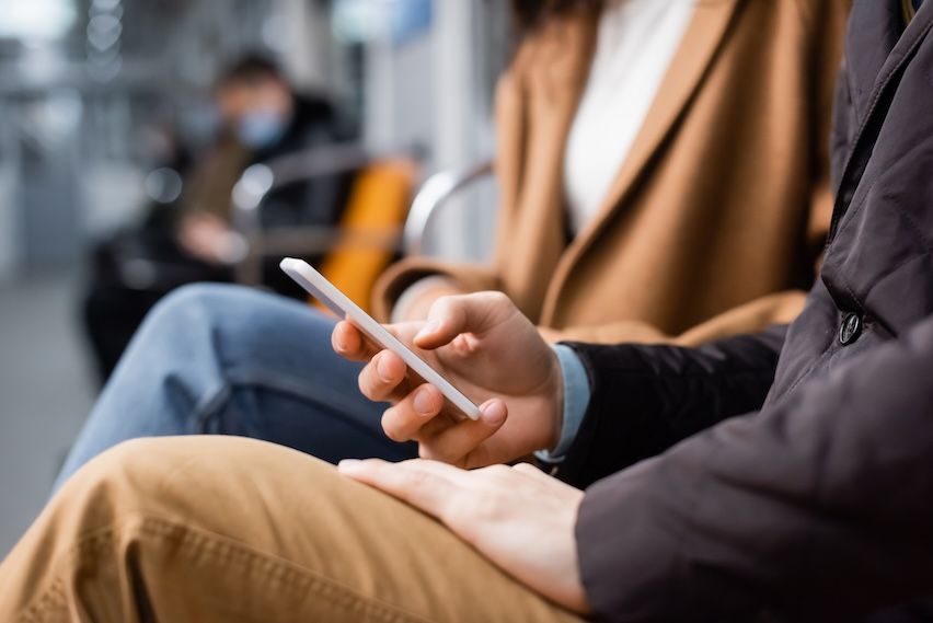 A man and a woman viewing a mobile-friendly email on a smartphone in a train, highlighting the need for responsive design in bulk email marketing.