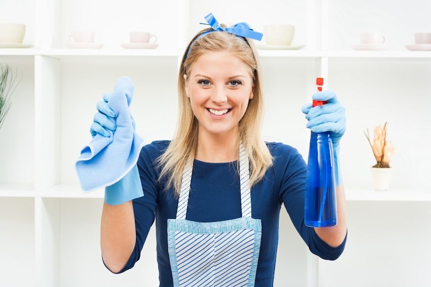 Smiling blond cleaning lady with supplies, symbolizing the importance of a clean email list.