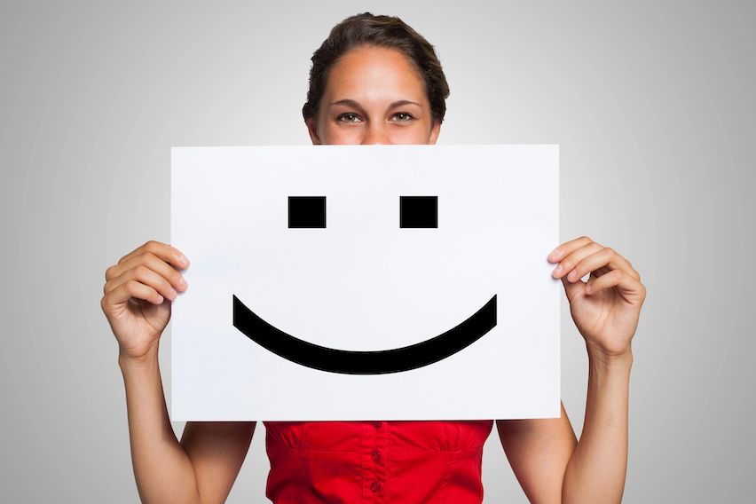 Woman holding a smiley face over her mouth, symbolizing enhanced customer satisfaction through email automation.