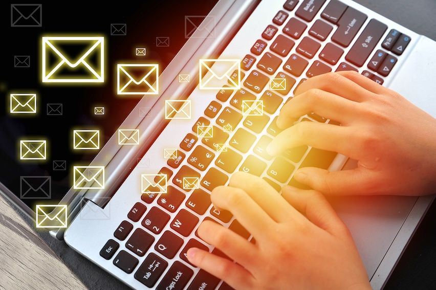 Hands typing on a glowing keyboard, creating bulk email campaigns, symbolizing the evolution of email marketing strategies