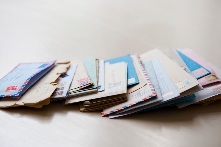 Pile of envelopes on a desk, showcasing the tangible aspect of direct mail marketing in a digital world.