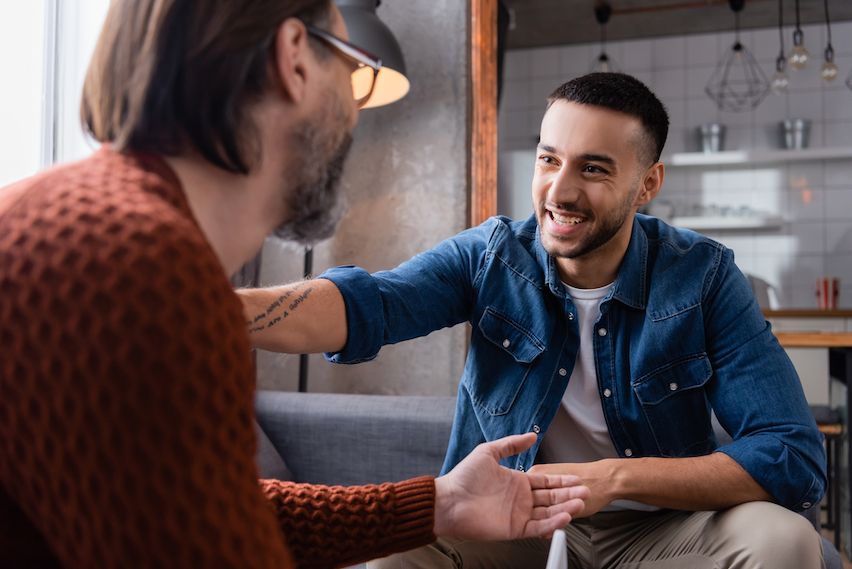 Two smiling small business owners engaging in a direct, positive conversation, symbolizing effective customer communication.