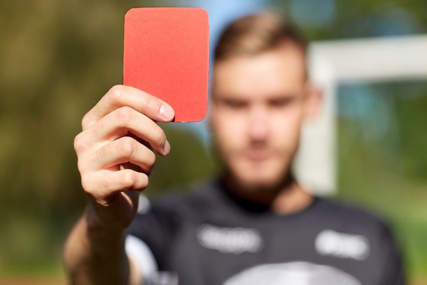 Referee holding up a big red card, symbolizing penalties for CAN-SPAM violations in email marketing.